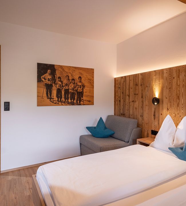 geräumiges Schlafzimmer mit Doppelbett in Holz, TV und Kästen. Blick zum Wilden Kaiser