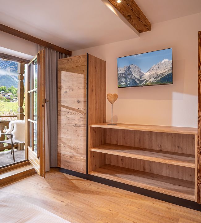 Schlafzimmer im Tiroler Stil mit viel Holz und Naturmaterialien. Blick vom Balkon zum Wilden Kaiser. TV